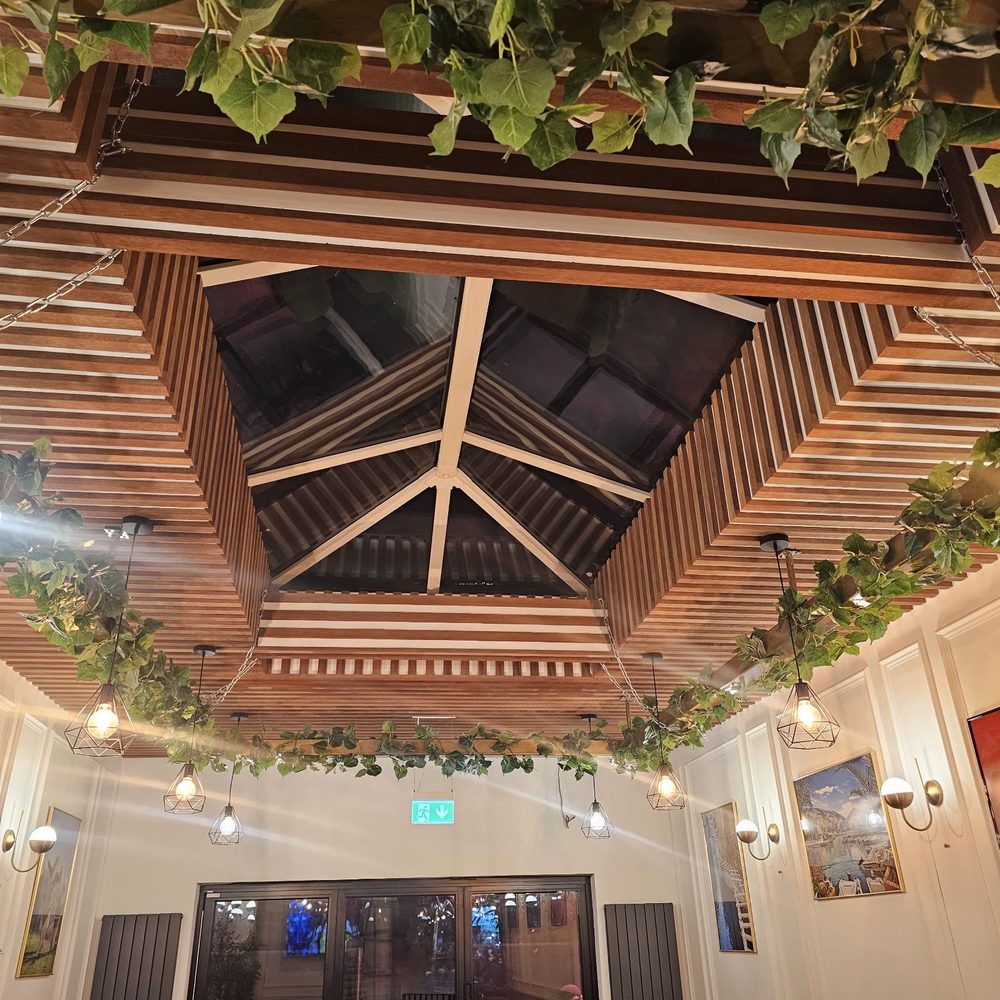 Looking up at the timber-slatted skylight with trailing ivy and festoon lights