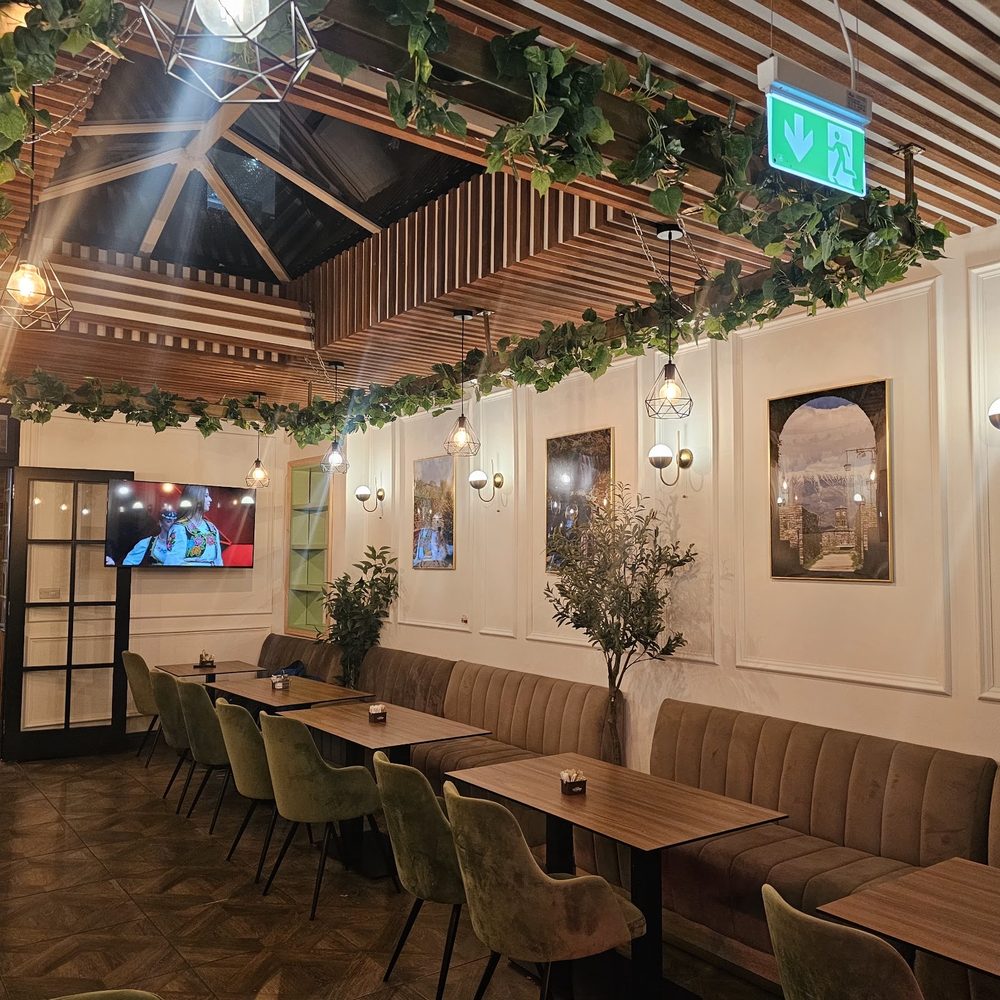 The dining room at Rio's Coffee Lounge, with banquette seating, olive trees and a slatted skylight ceiling